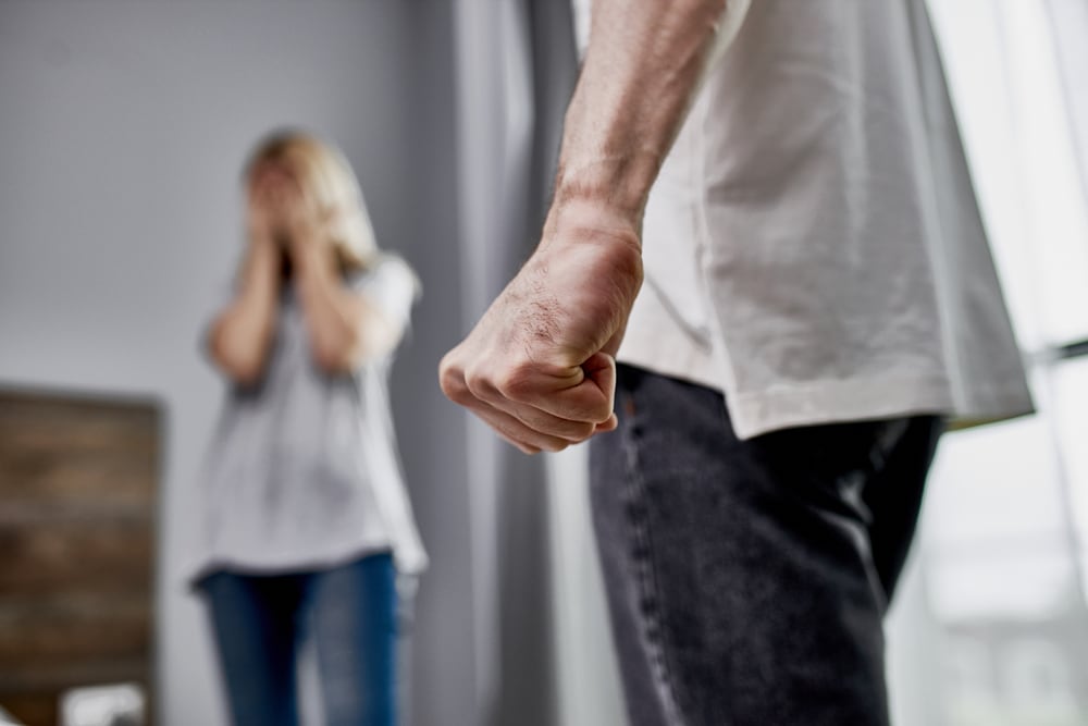 Domestic violence victim in room with man with a clenched fist