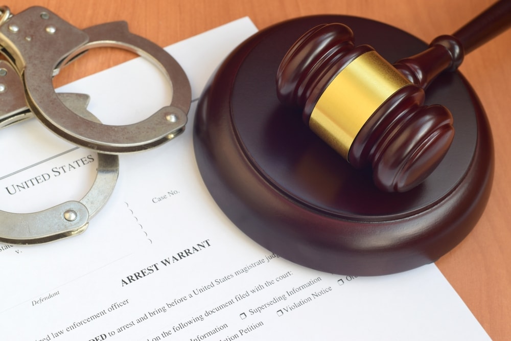 Closeup of a criminal defense lawyer's desk containing a gavel, handcuffs, and case documents