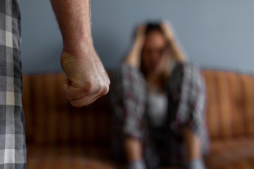 Closeup of man clenching a fist at a woman in the background