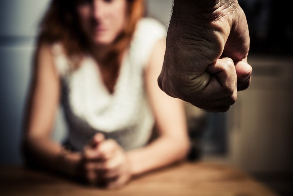 Closeup of man clenching a fist at a woman in the background