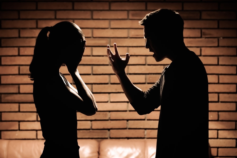 Silhouettes of a couple engaging in verbal abuse